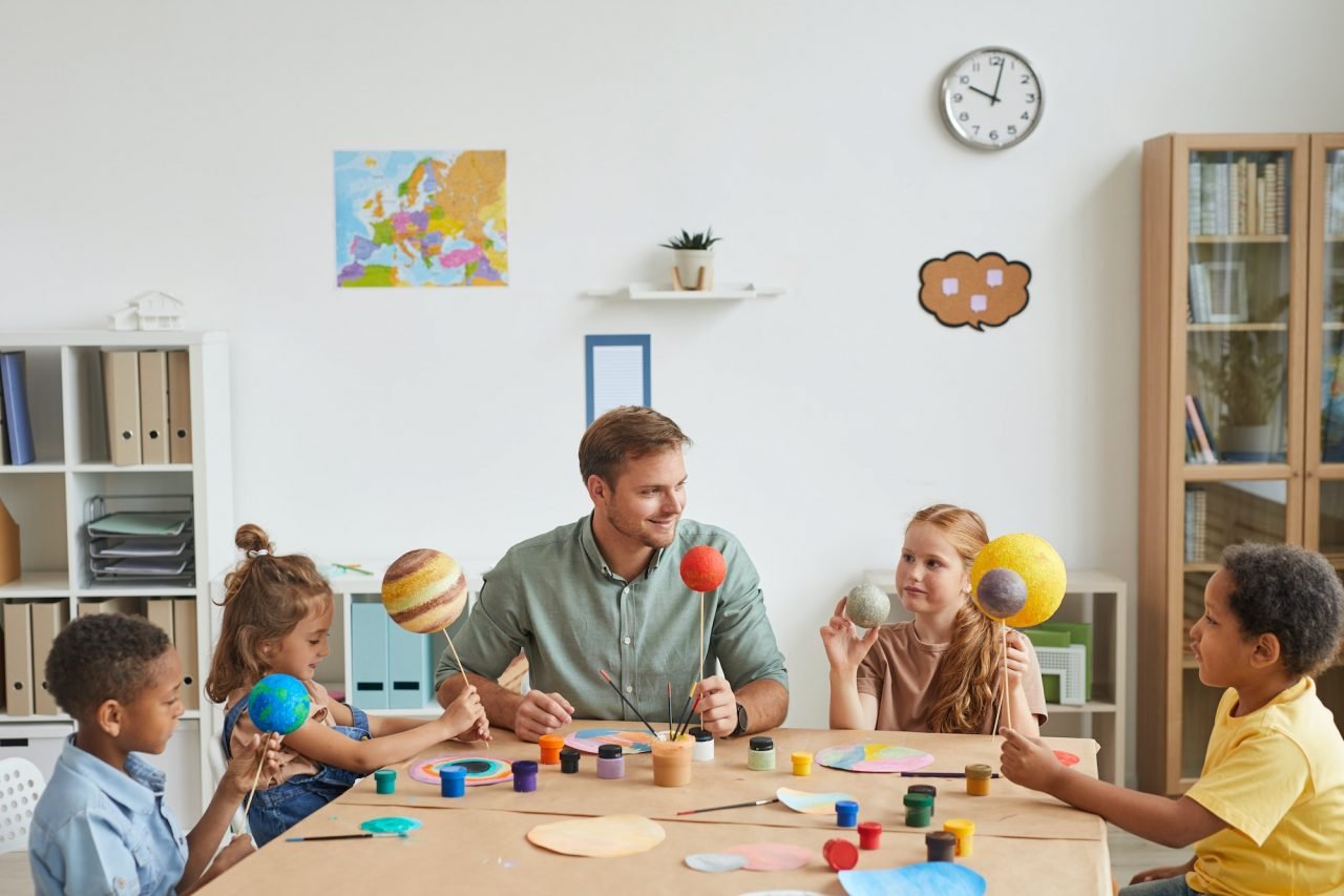 Kids playing with model planets in art and craft class